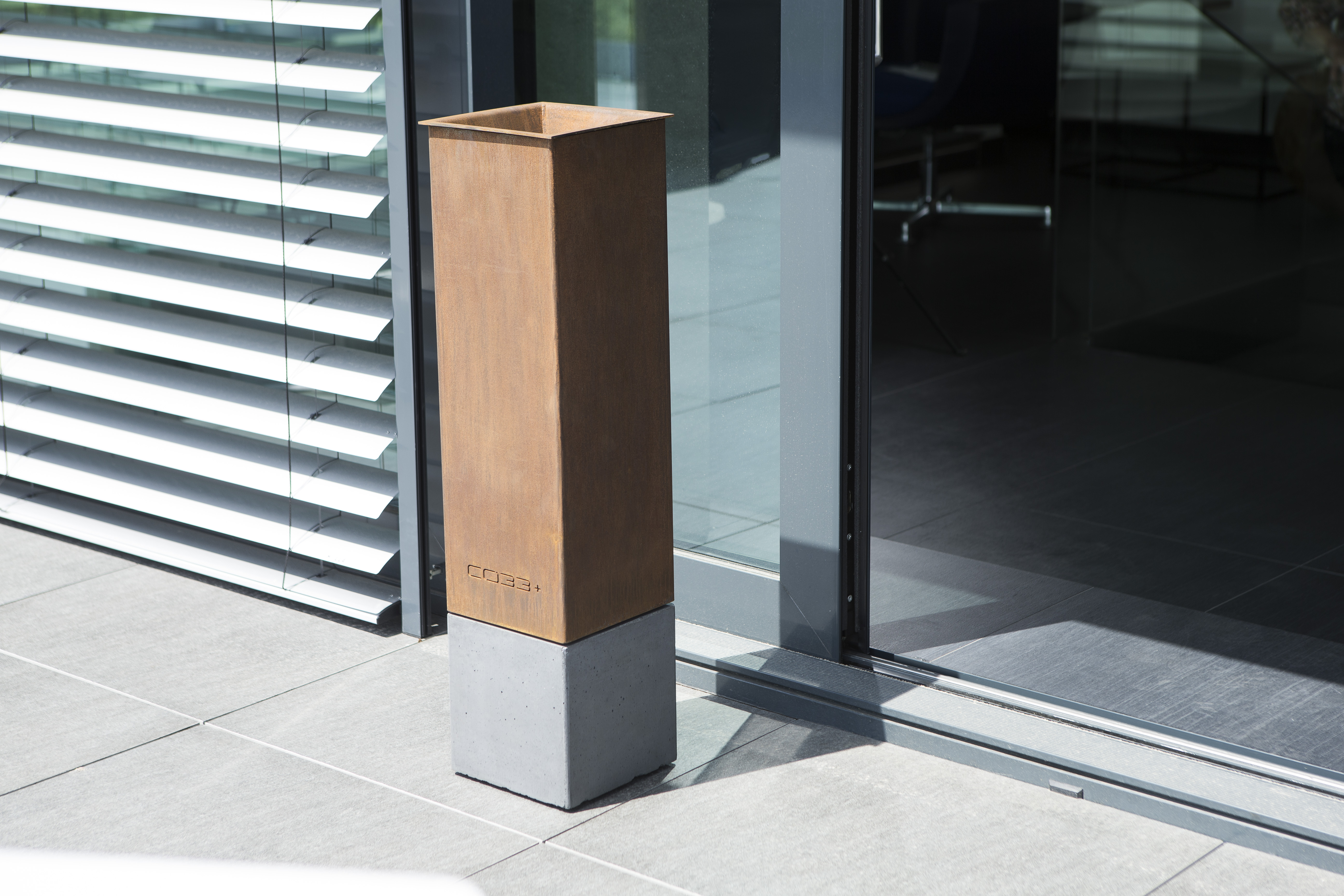 minimalistischer Standascher aus Cortenstahl und dunkelgrauem Beton im Bauhaus Stil