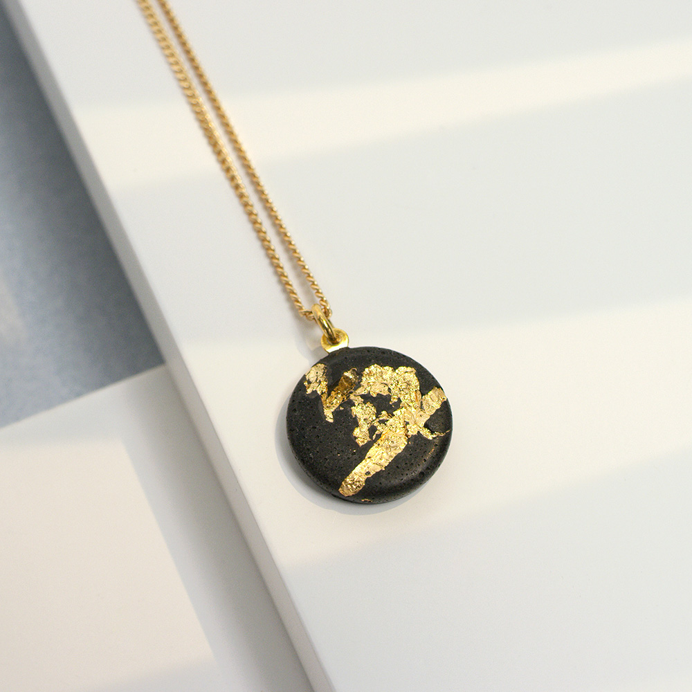 designer necklace with black concrete circle pendant and gold leaf