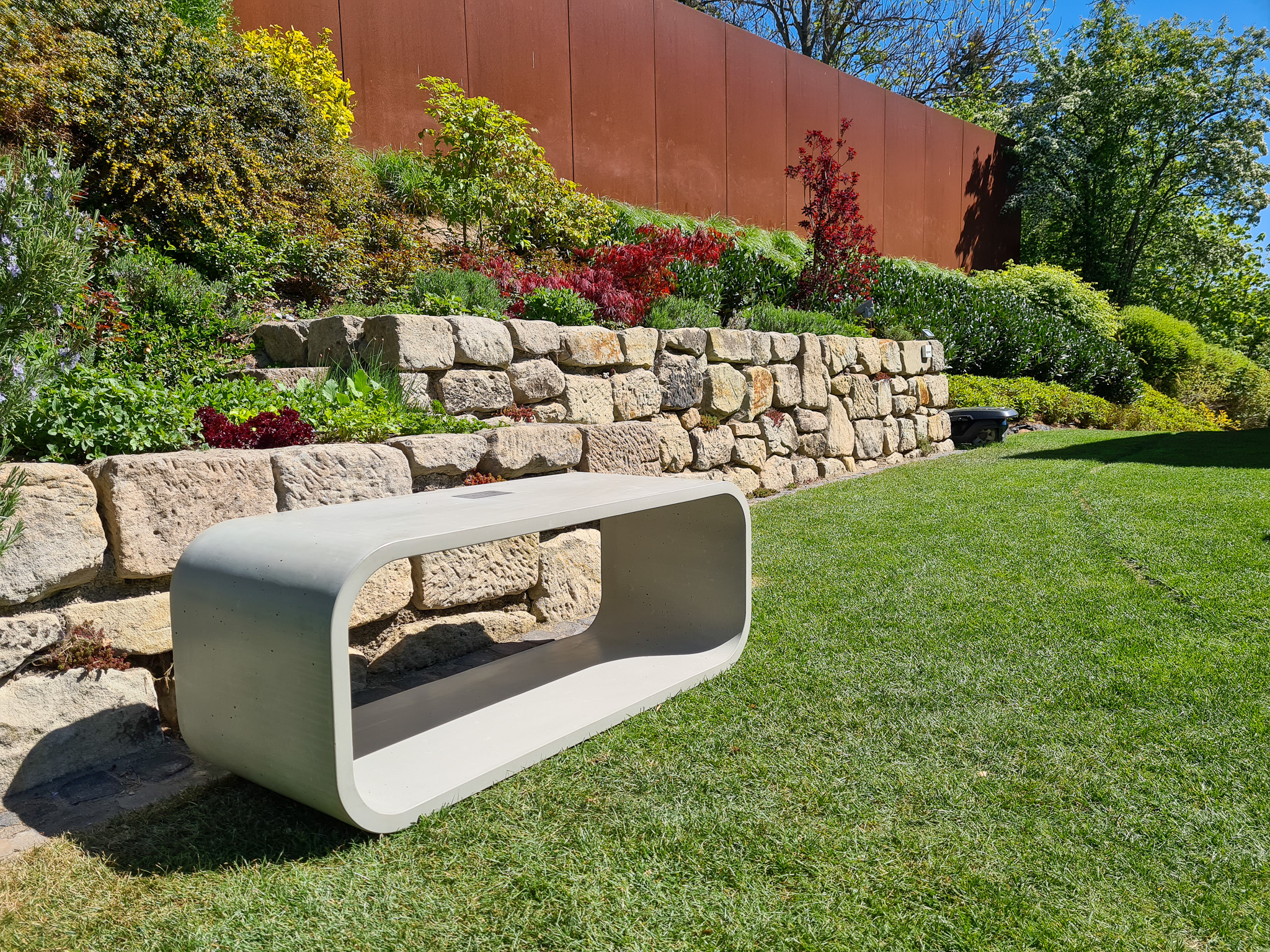 moderne Betonbank im grünen Garten 