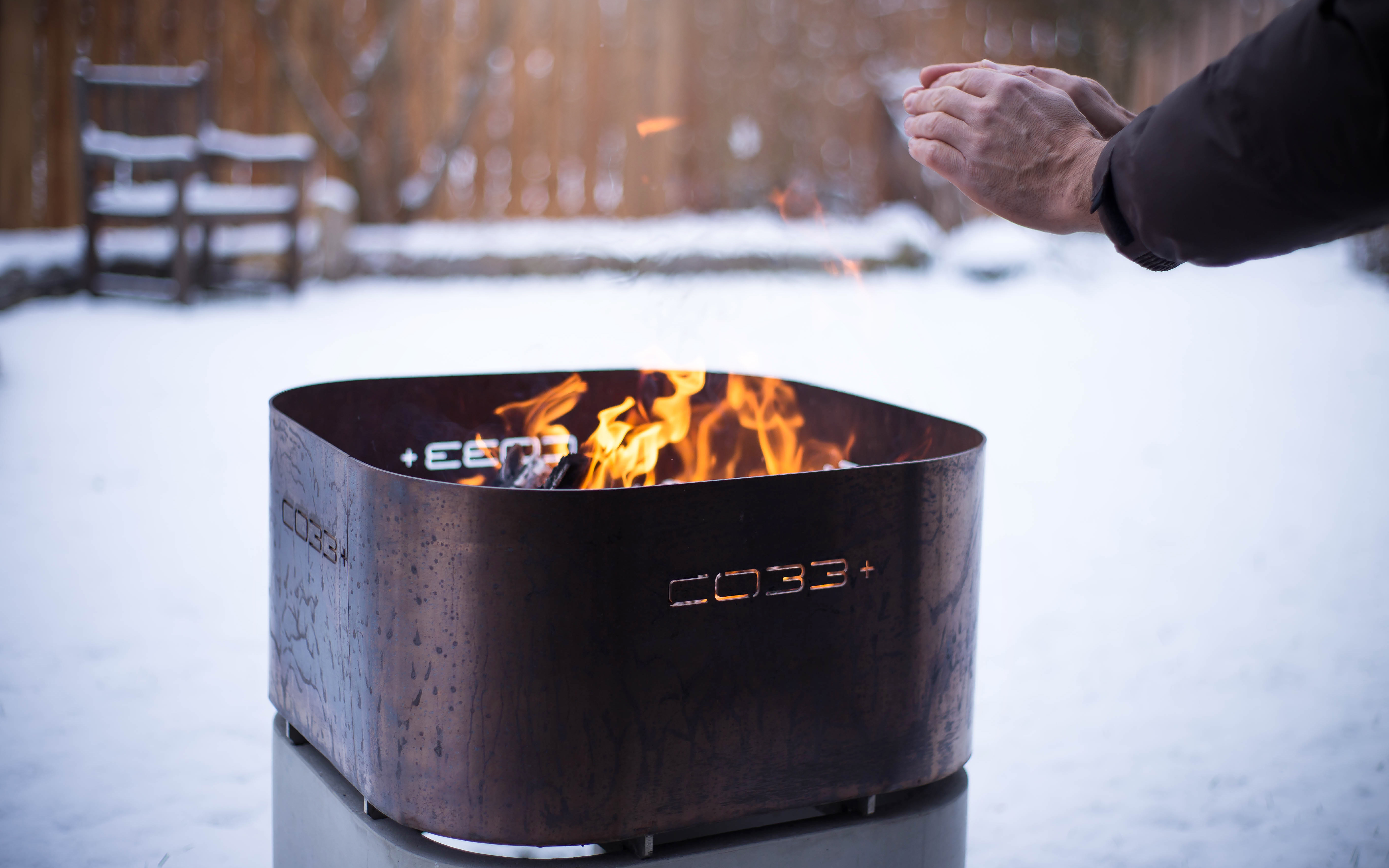 Firebowl made of concrete and stainless steel in use for warmth during winter