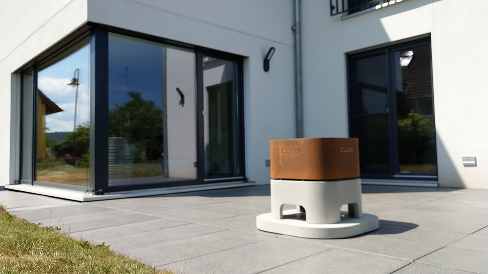 Grey concrete and Corten steel fire bowl with concrete foundation plate